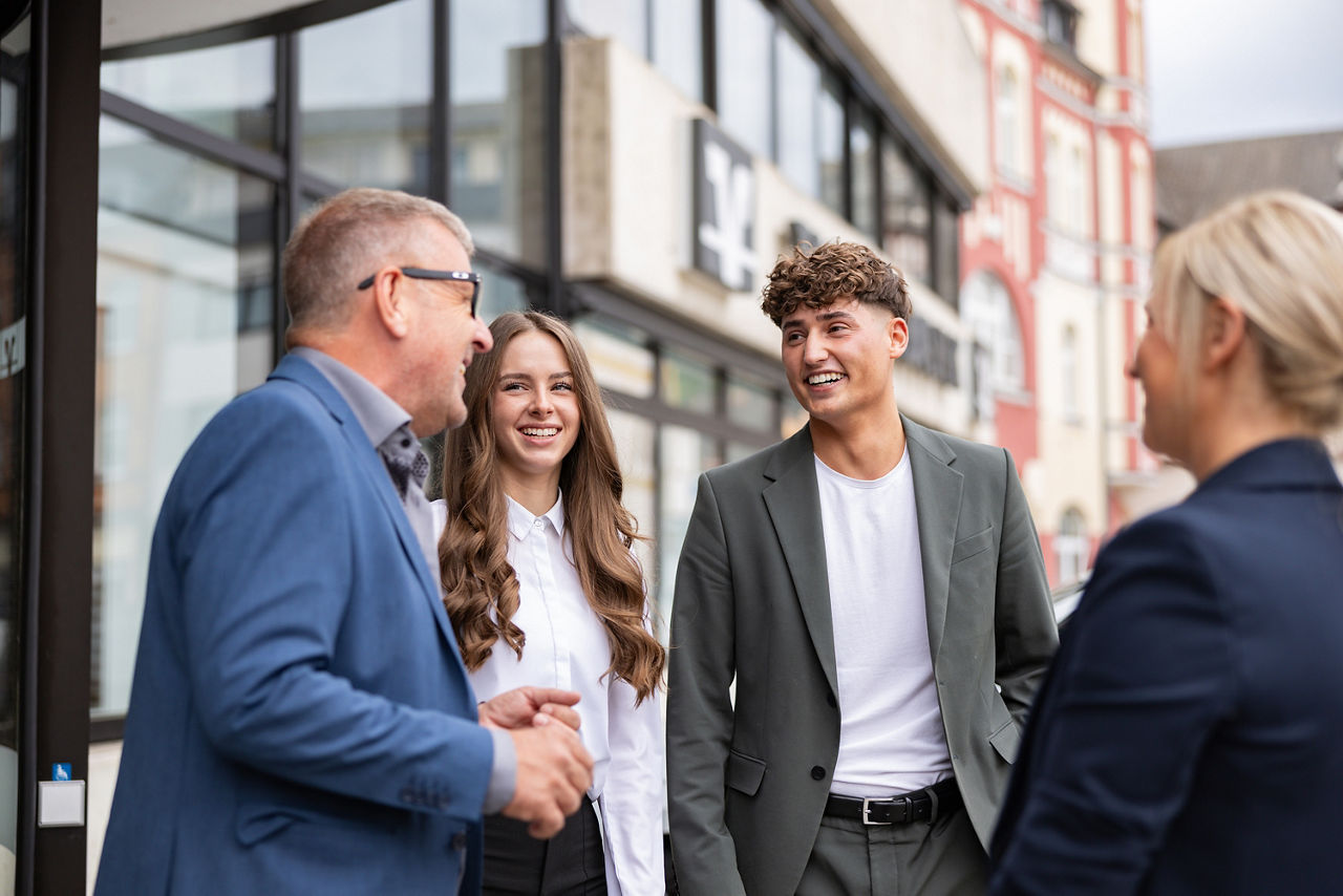 Eine fröhliche Gruppe von Menschen in einem Gespräch vor einer Volksbank