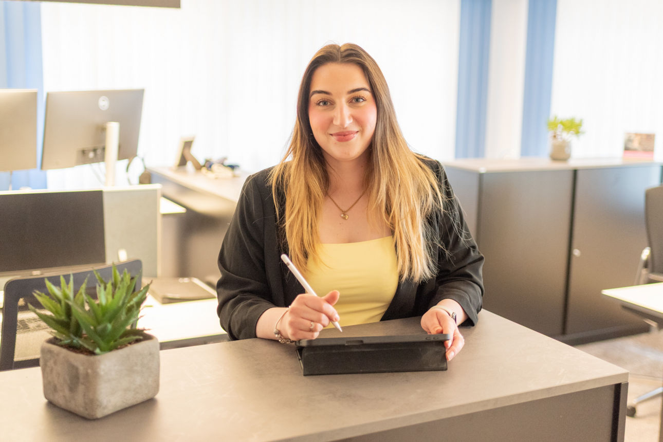 Junge Frau steht mit dem iPad und einem Stift in der Hand an einem Hightable