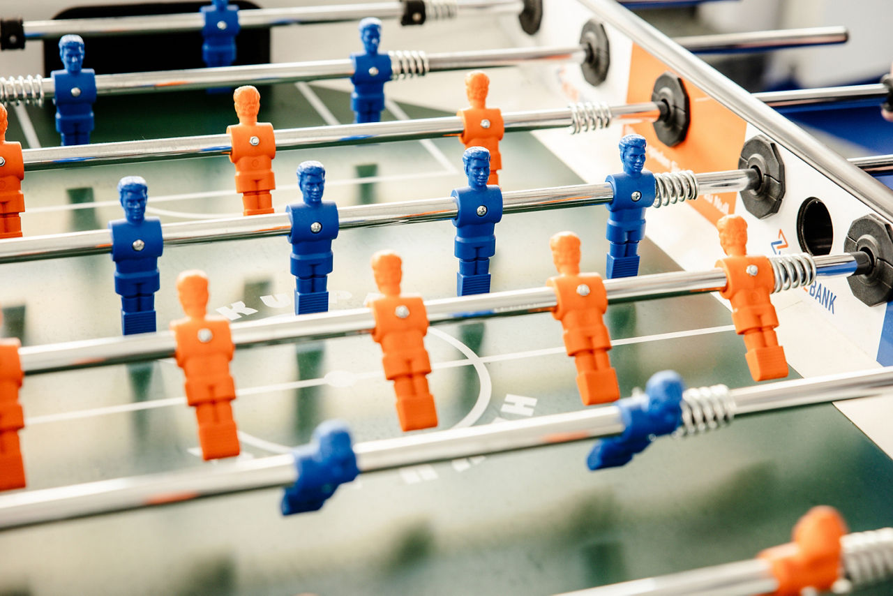 Abbildung zeigt einen Tischkicker mit orangenen und blauen Spielern