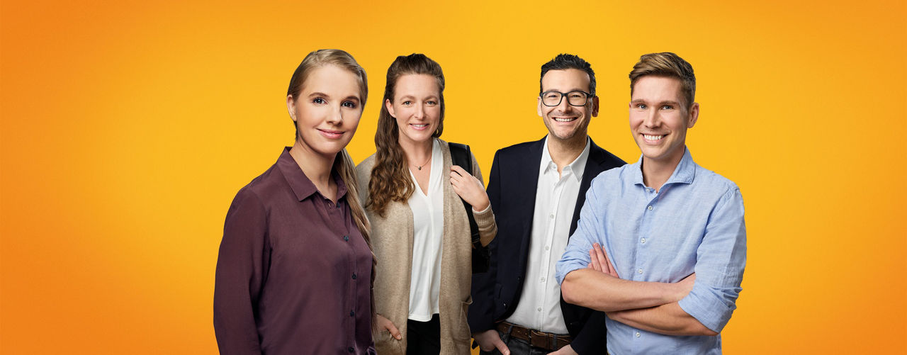 Zwei Frauen und zwei Männer stehen lächelnd nebeneinander.