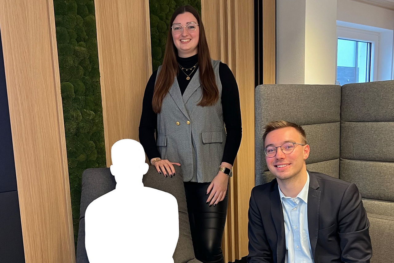 Junge Frau und junger Mann sitzen und stehen lächelnd um weißen Avatar herum. 