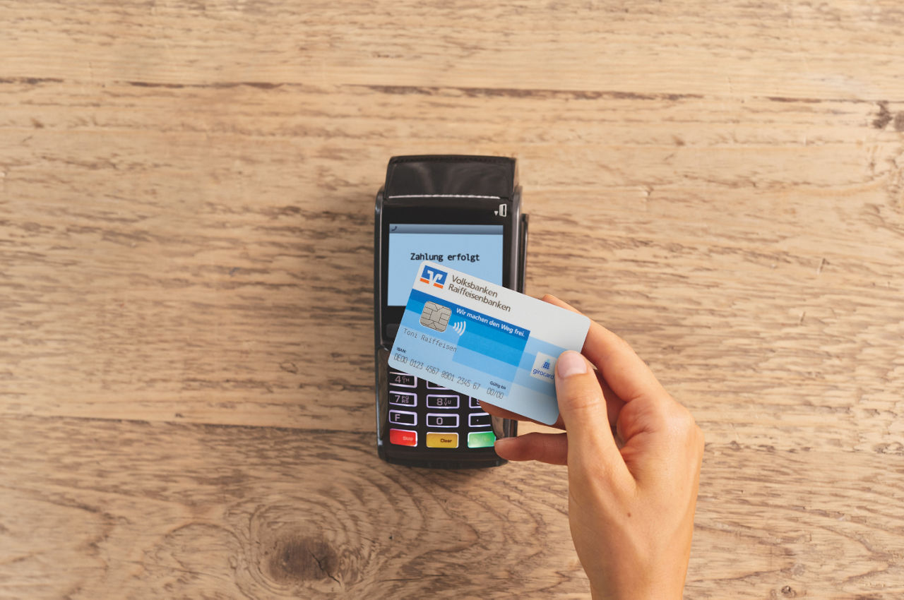 Debitkarte auf EC-Cash Gerät auf Holzhintergrund