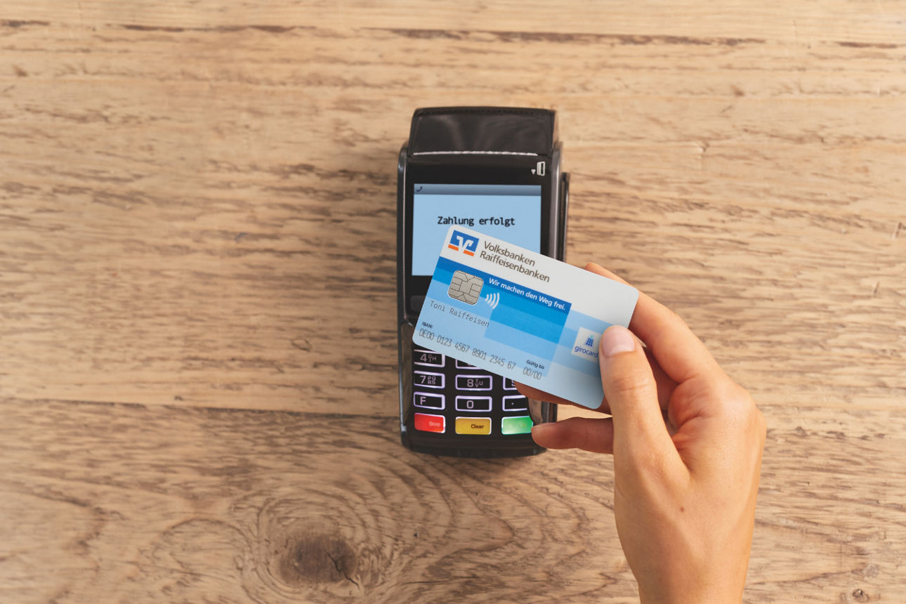 Debitkarte auf EC-Cash Gerät auf Holzhintergrund