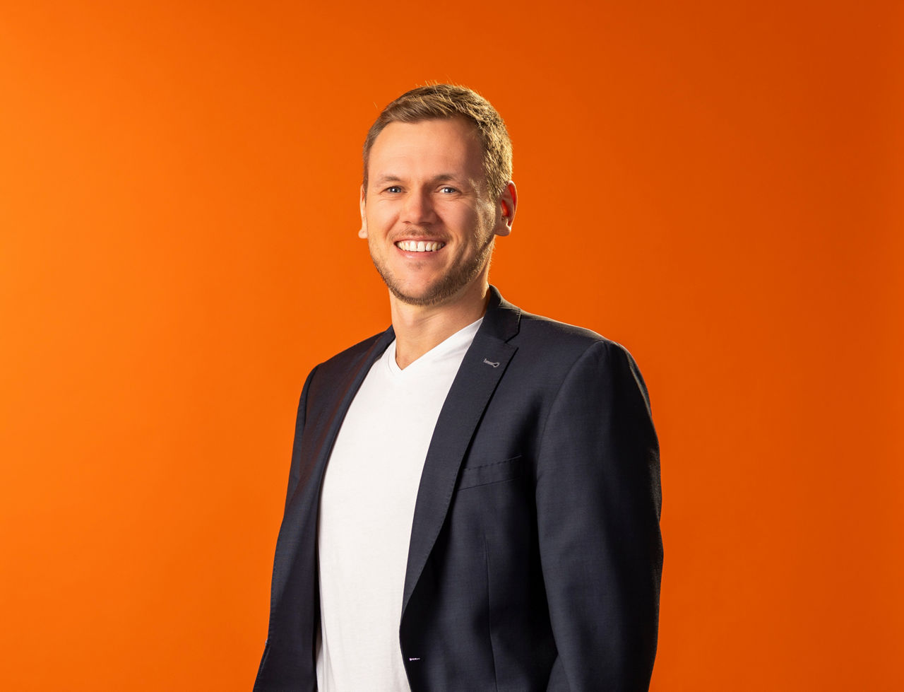 Bild unseres Mitarbeiters Michael Keller vor einer orangenen Wand