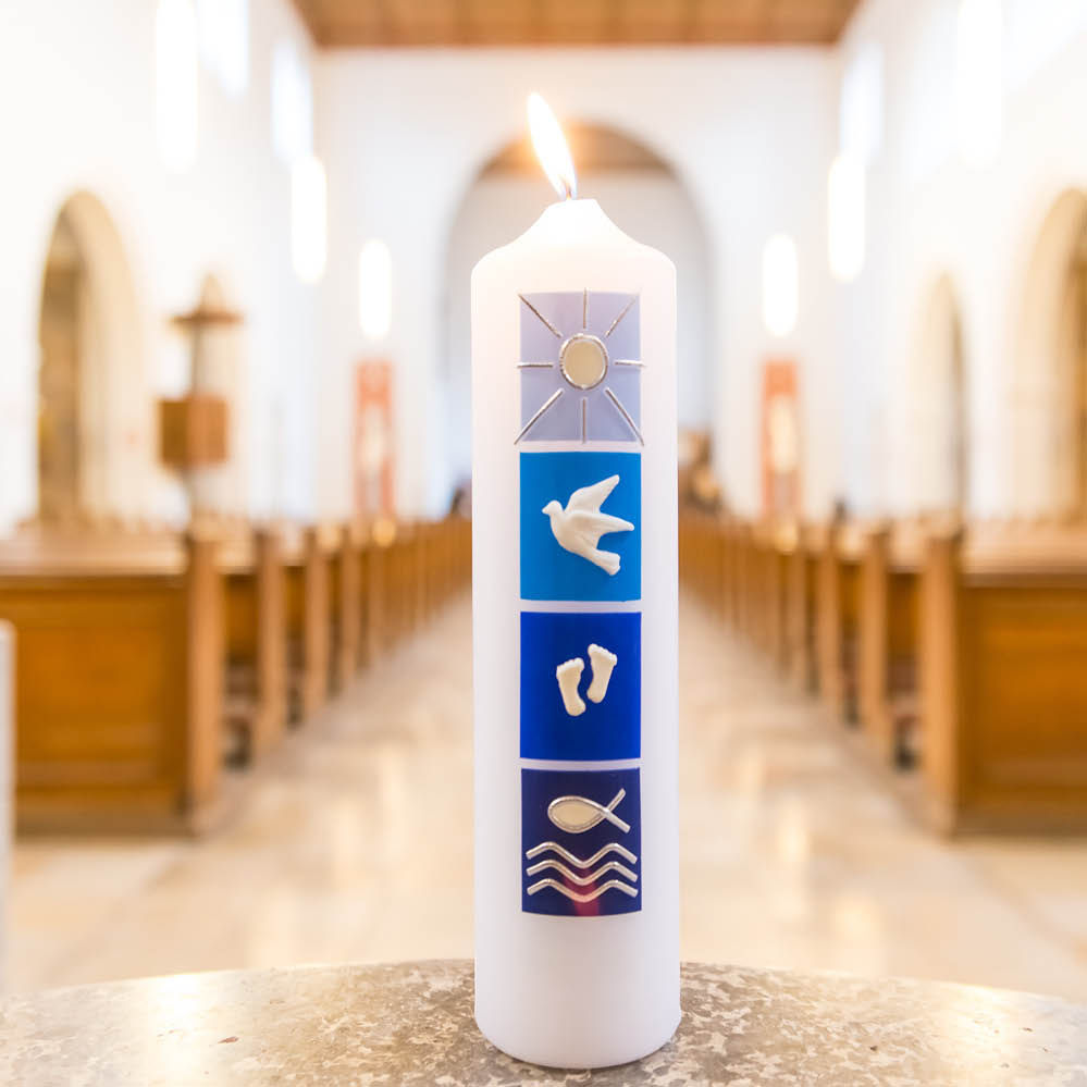 Eine Kerze mit Sitzbänken einer Kirche im Hintergrund.
