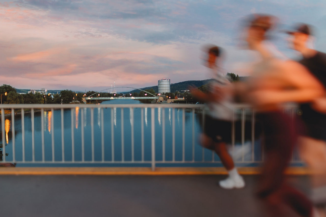 Running-Team joggt in der Abenddämmerung über eine Brücke.