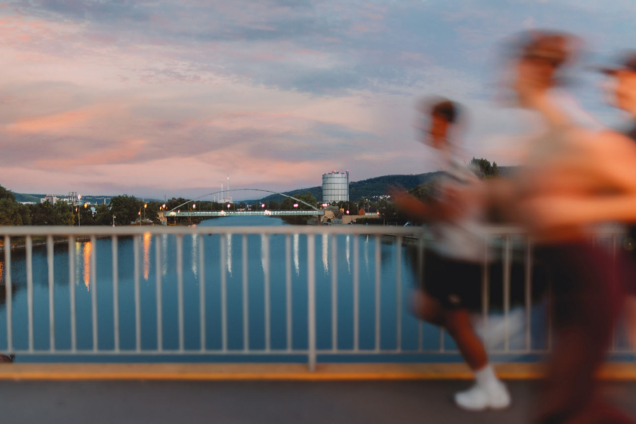 Gruppe von Läufer in der Abenddämmerung auf einer Brücke über den Neckar.