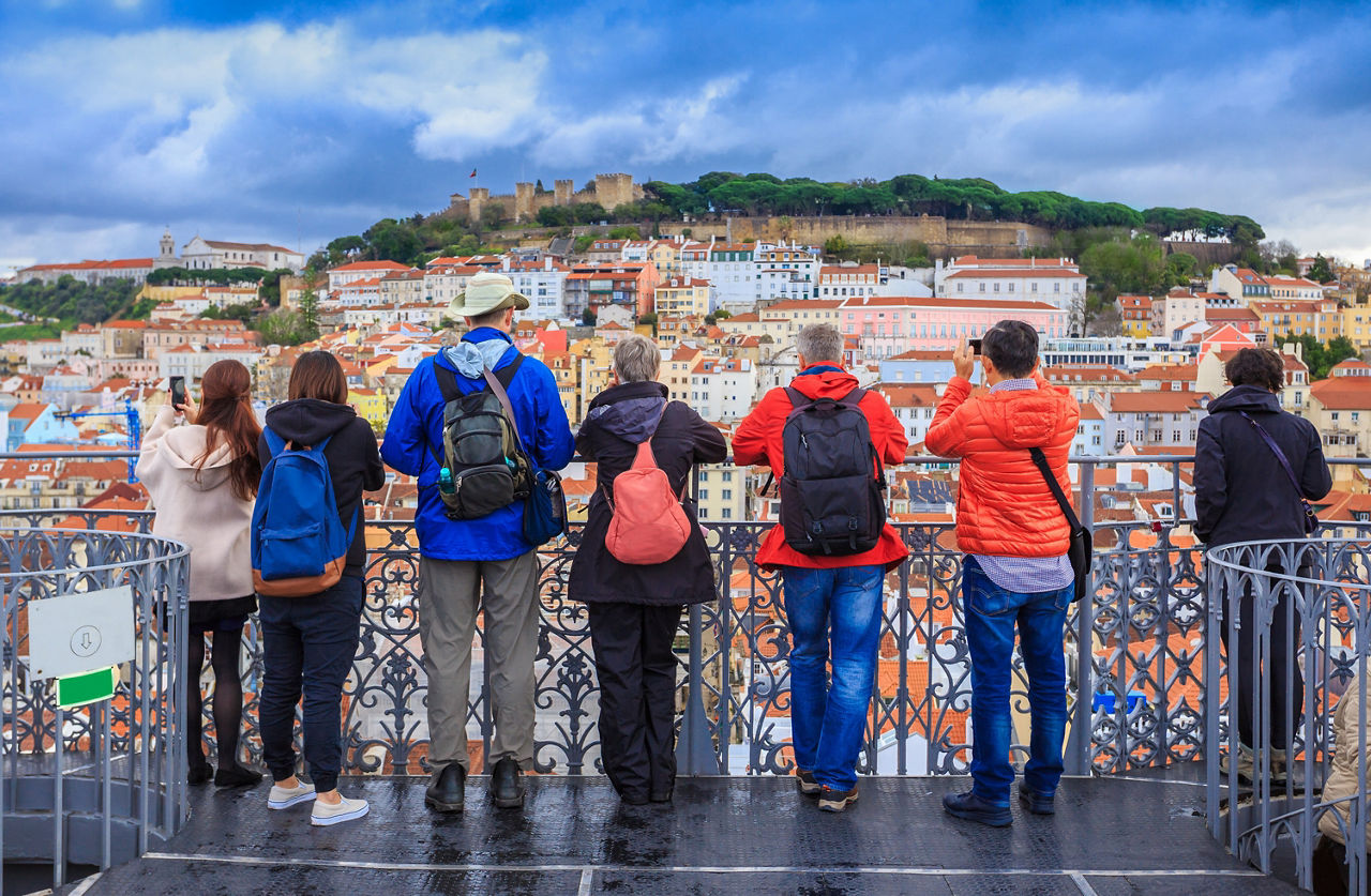 Gruppe von Touristen, die das Stadtbild von Lissabon beobachten und Fotos der Burg Sao Jorge in Portugal machen.