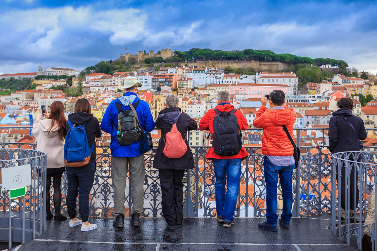 Gruppe von Touristen, die das Stadtbild von Lissabon beobachten und Fotos der Burg Sao Jorge in Portugal machen.