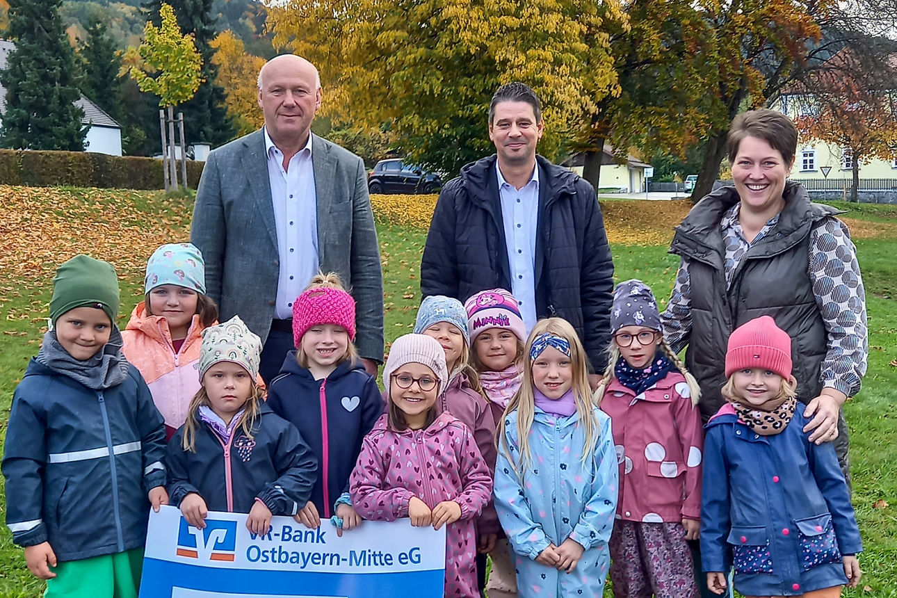 Drei  Erwachsene und ein paar Kinder stehen vor ein paar Bäumen und halten eine Spendentafel über 500 Euro hoch
