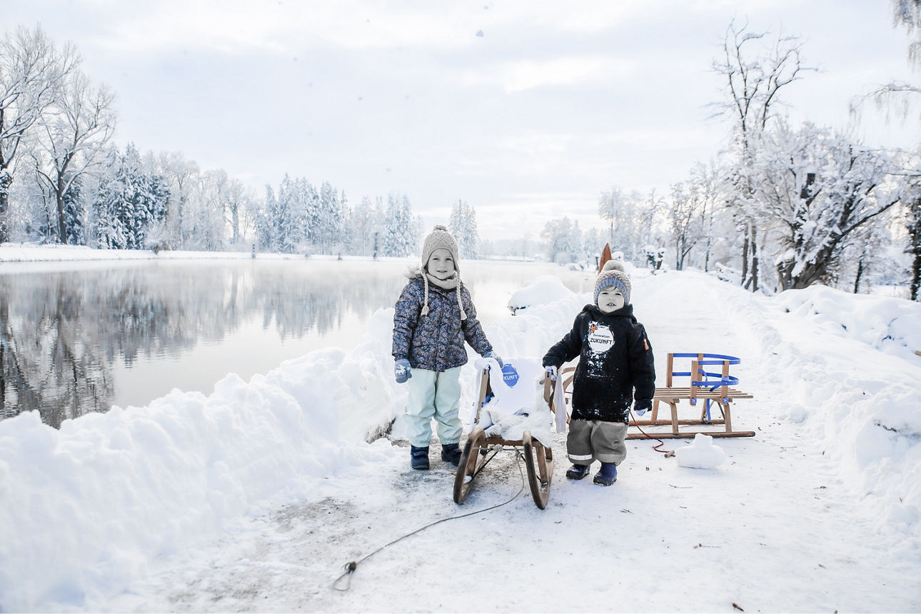 Zwei Kleinkinder mit ihren Schlitten im Schnee