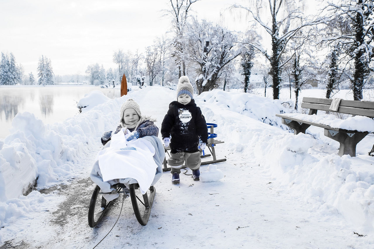 Zwei Kleinkinder mit ihren Schlitten im Schnee
