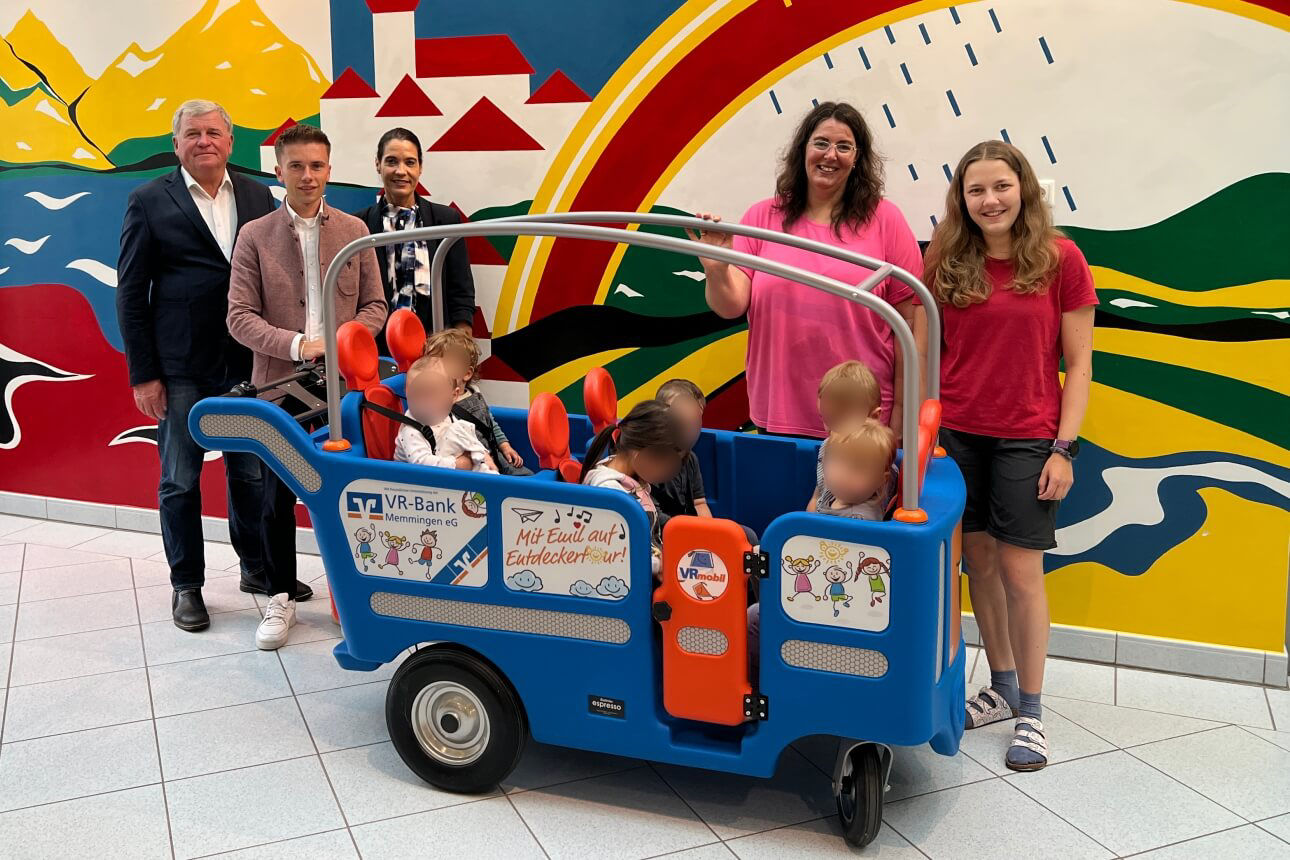 Kindergartenkinder sitzen in Emil Bus und Erzieher, Bankmitarbeiter und Bürgermeister dahinter