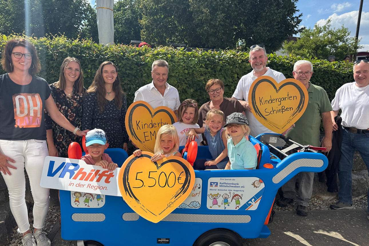 Gruppe von Menschen mit blauem Wagen und Herzschildern, Spendensumme 5.500 Euro angezeigt