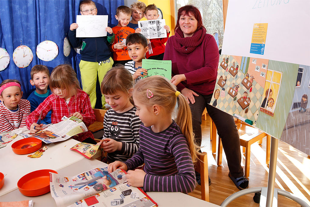 Eine Kindergartengruppe mit Ihrer Erzieherin an einem Basteltisch