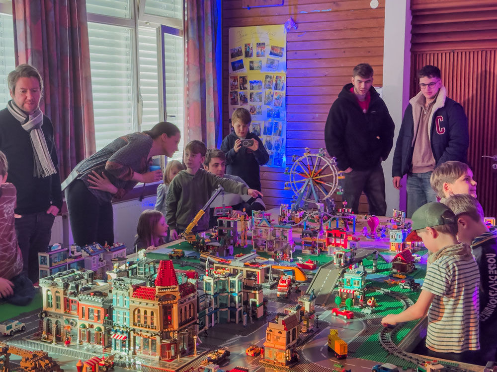 4 Erwachsene und eine Gruppe von Kindern vor einer Modellstadt mit Häusern und einem Riesenrad