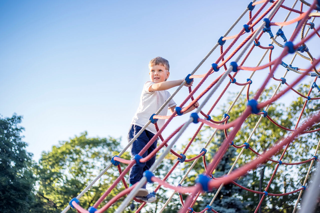 Kind klettert auf einem Spielplatz
