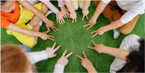 Kinder sitzen im Kreis und versuchen mit ihren Händen einen großen Stern zu zeigen