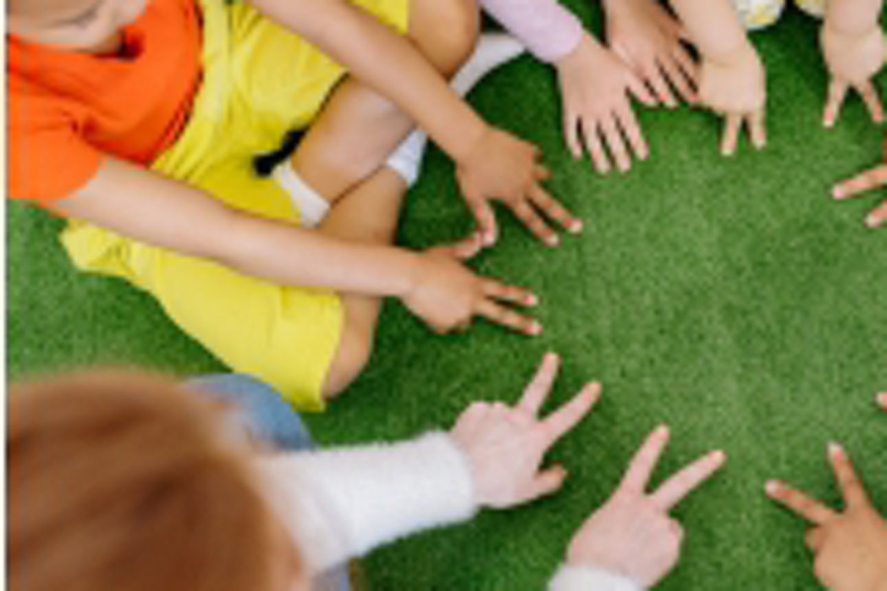 Kinder sitzen im Kreis und versuchen mit ihren Händen einen großen Stern zu zeigen