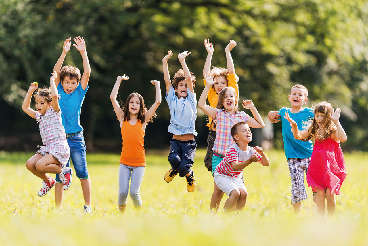 Neun Kinder die in die Luft springen und die Hände hoch halten