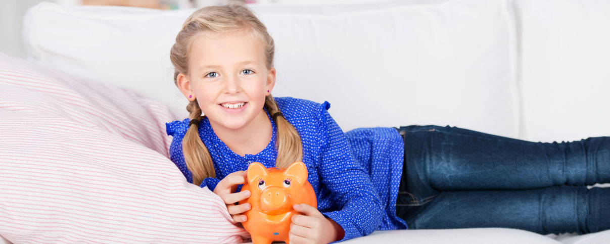 liegendes Mädchen mit Sparschwein