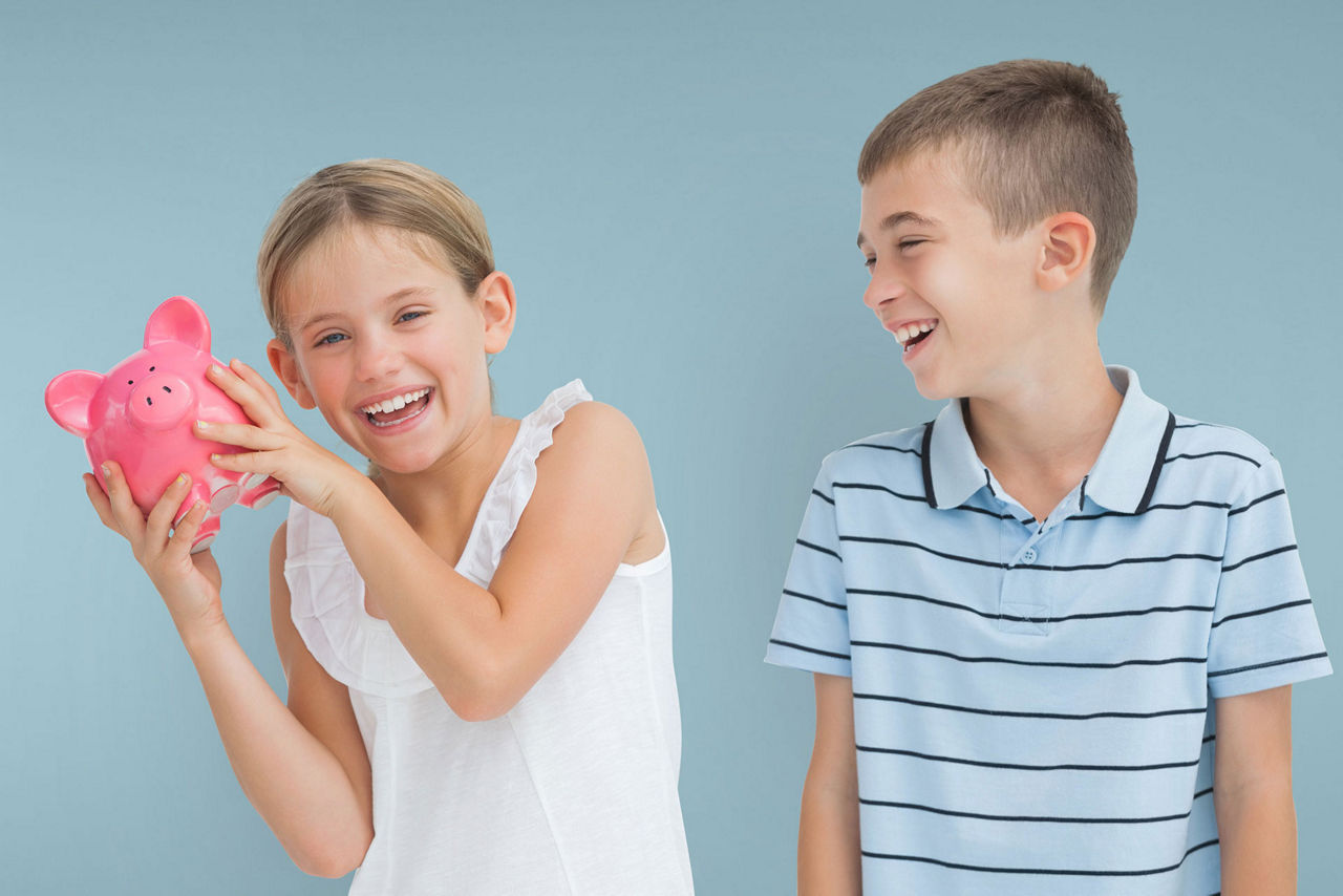 Zwei Kinder mit einem pinken Sparschwein lachen