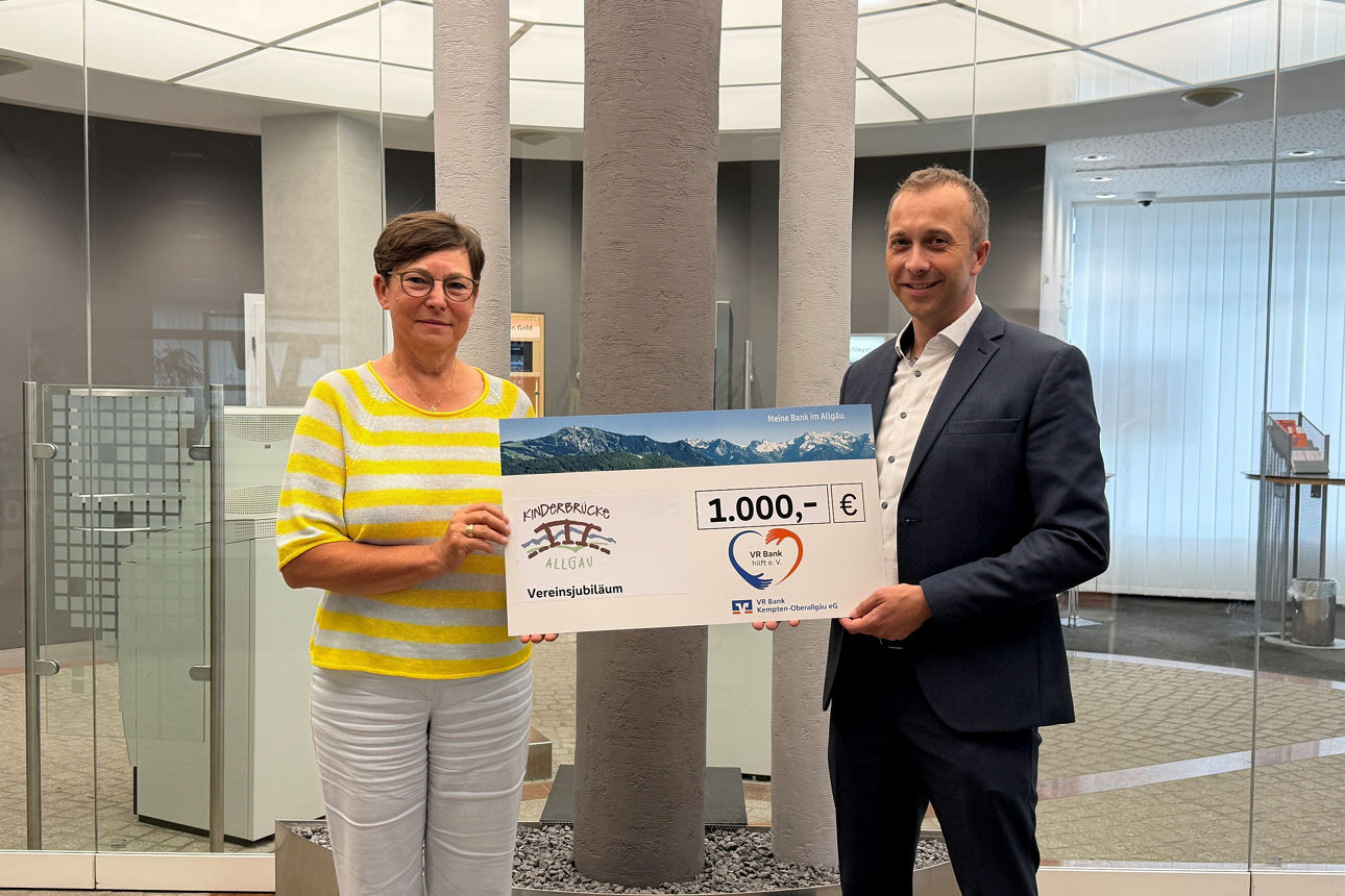 Vereinsjubiläum - Preisübergabe VR Bank hilft e. V. an Kinderbrücke Allgäu - 2 Personen mit Scheck