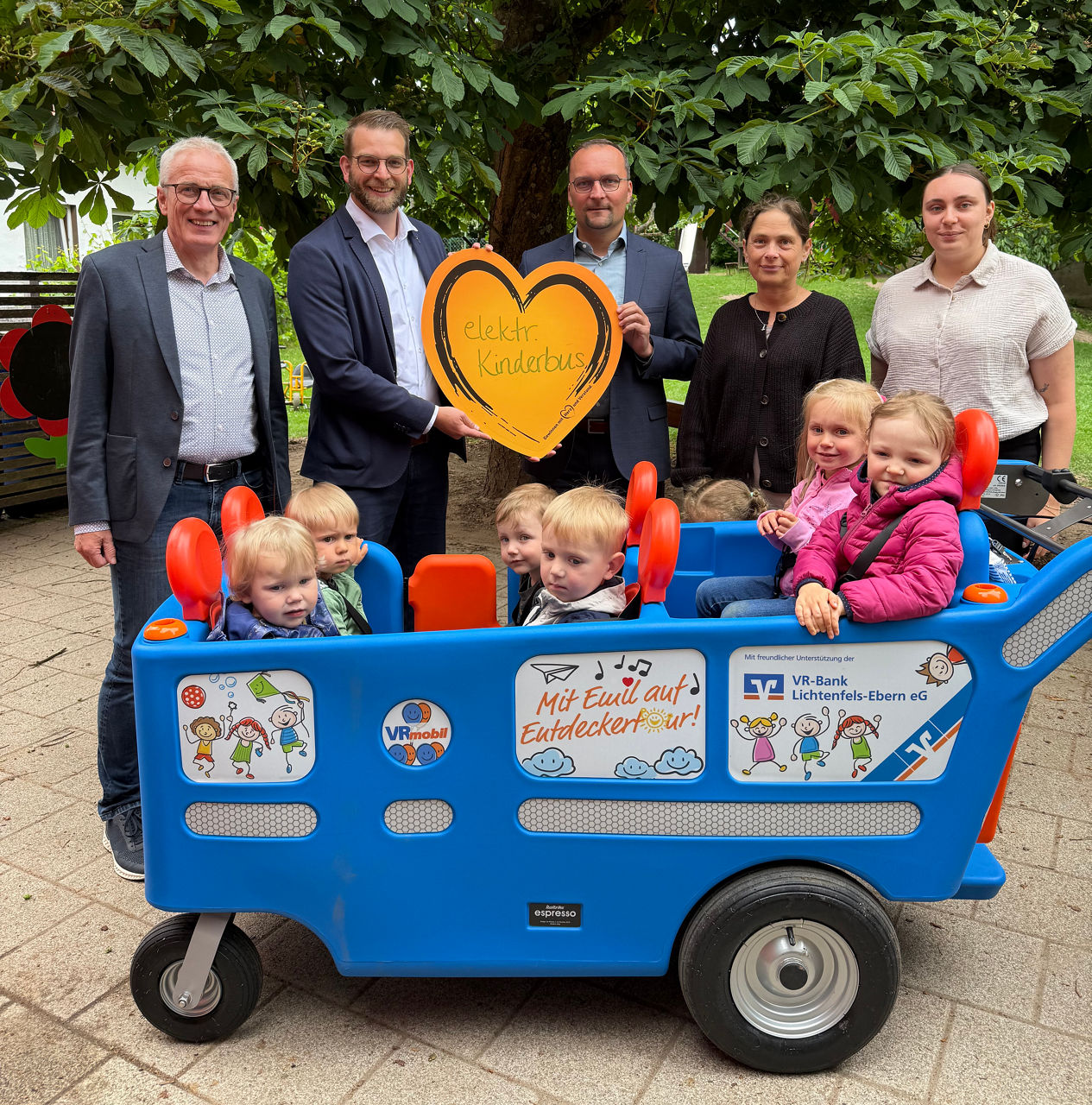Kindergartenkinder sitzen bei einer Spendenübergabe im elektrischen Kinderbus