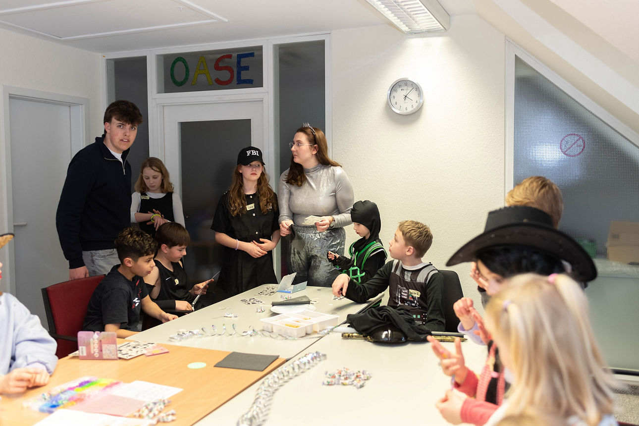 Verkleidete Kinder basteln an einem Tisch.