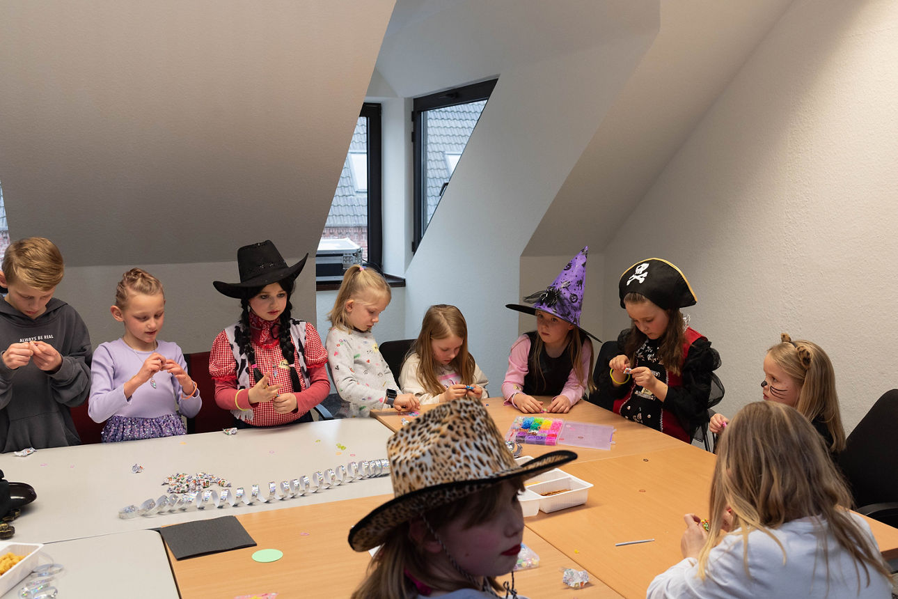 Verkleidete Kinder basteln an einem Tisch.