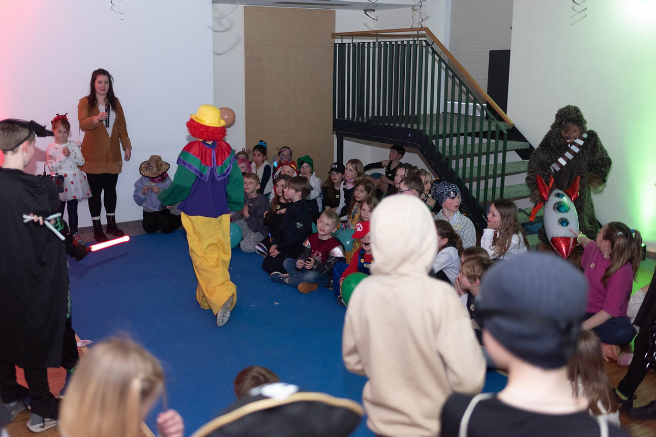 Ein Clown läuft auf einem blauen Laufsteg.