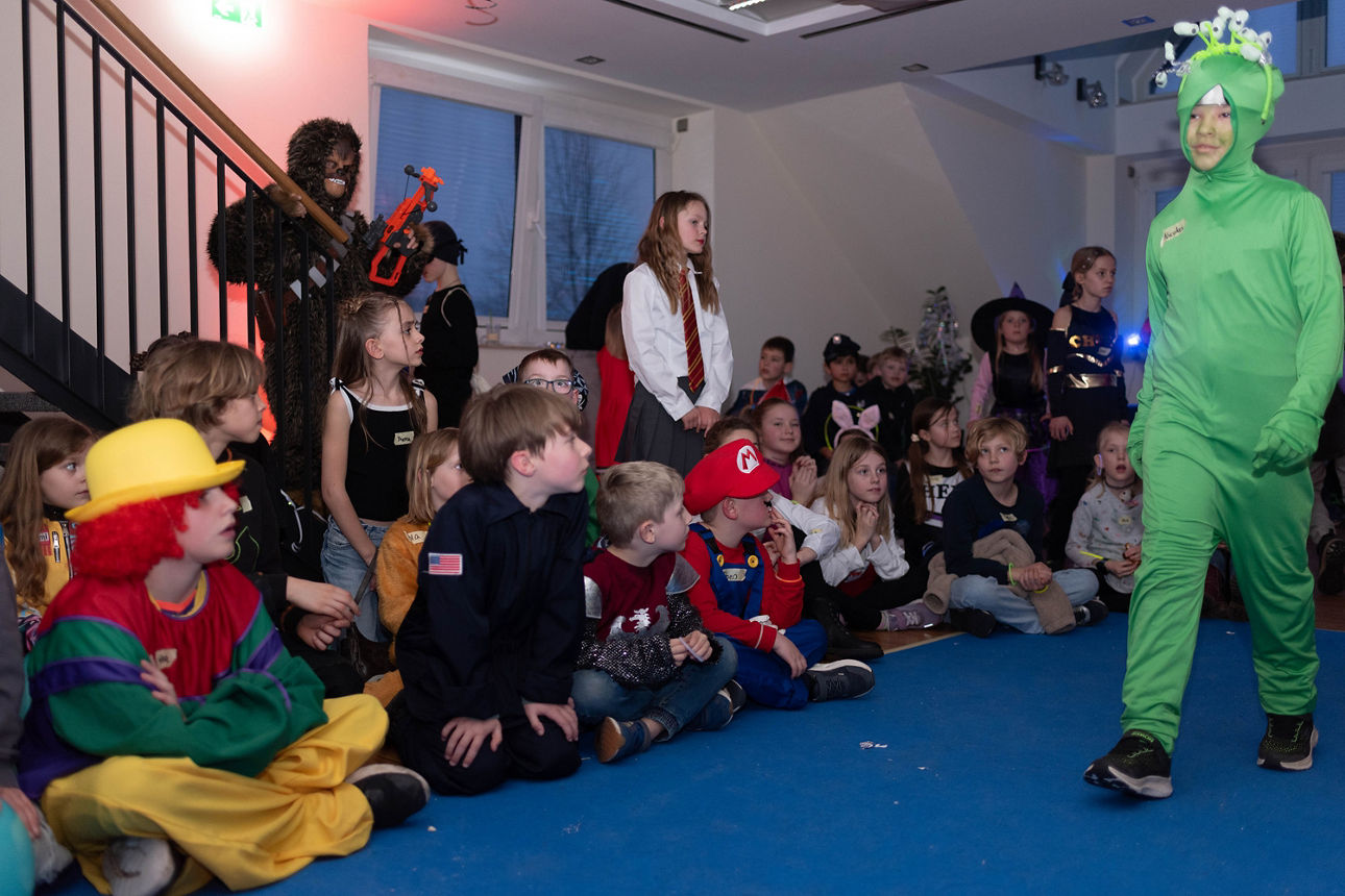 Ein Alien läuft auf einem blauen Laufsteg. 