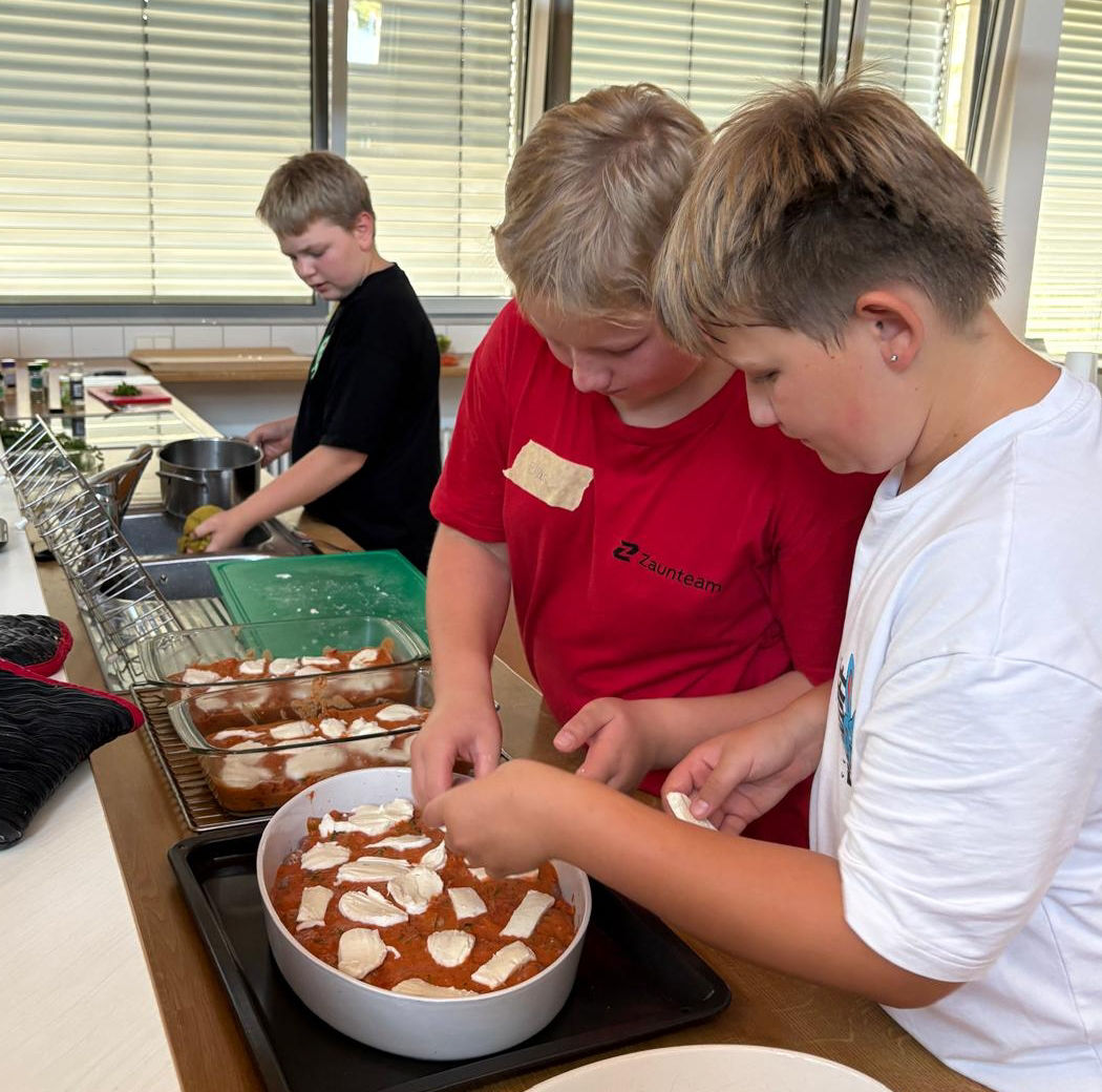 Jungsgruppe belegt Hackbällchen mit Käse