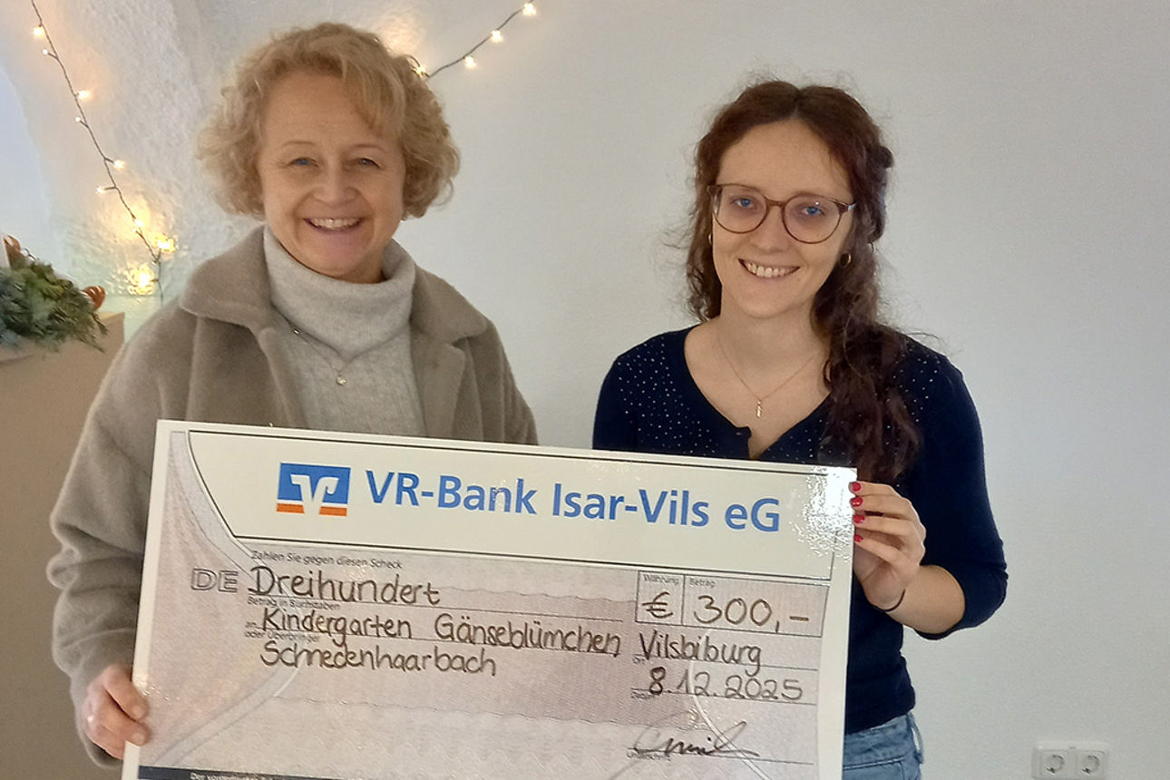 Zwei junge Frauen lachen in die Kamera. Sie halten einen Riesenspendenscheck in der Hand.