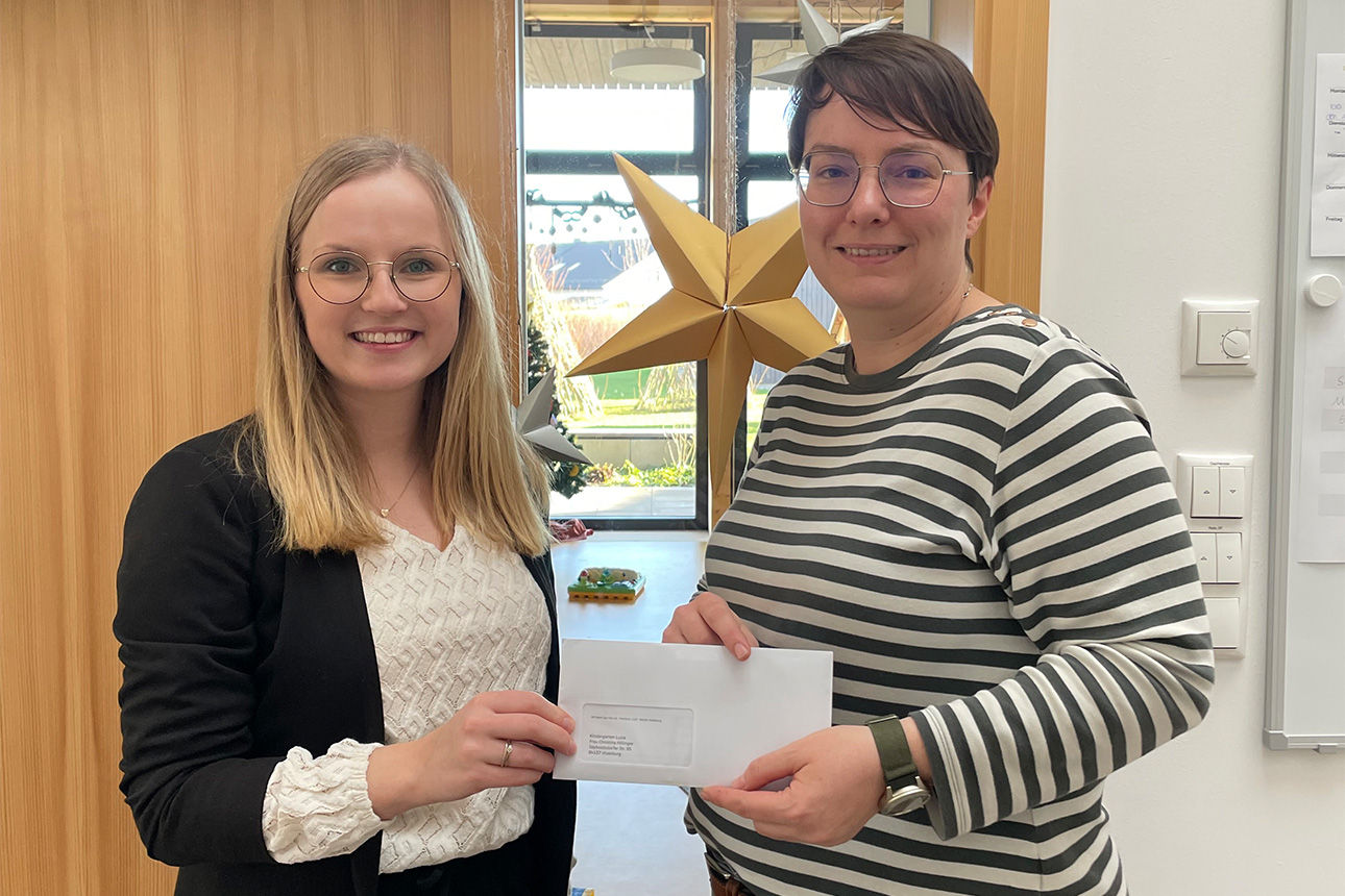 Zwei junge Frauen lachen in die Kamera. Sie halten einen Briefumschlag in der Hand.