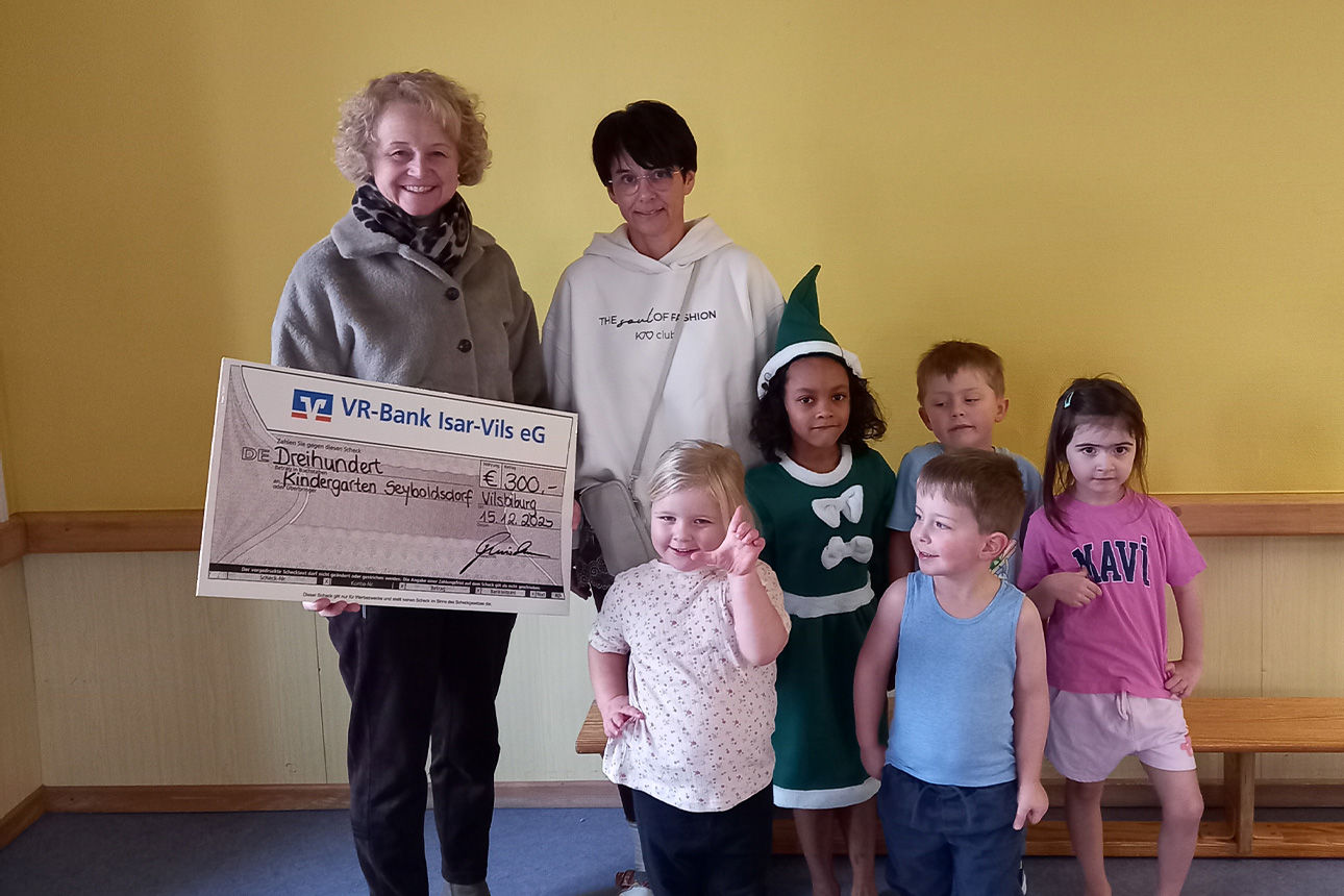 Zwei Frauen und fünf Kinder lachen in die Kamera. Sie halten einen Riesenspendenscheck in der Hand.