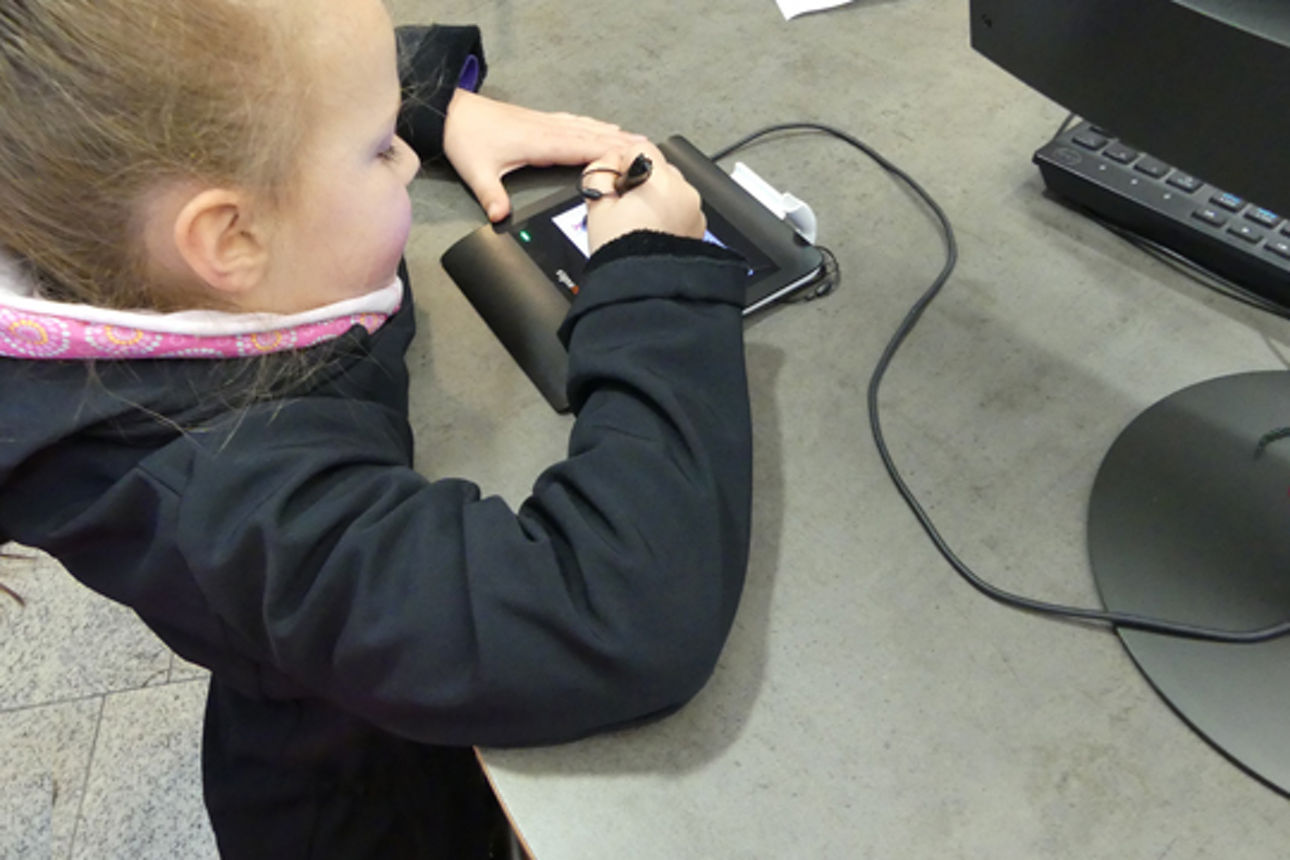 Ein blondes Mädchen am Schalter wärend sie auf dem Penpad unterschreibt. 