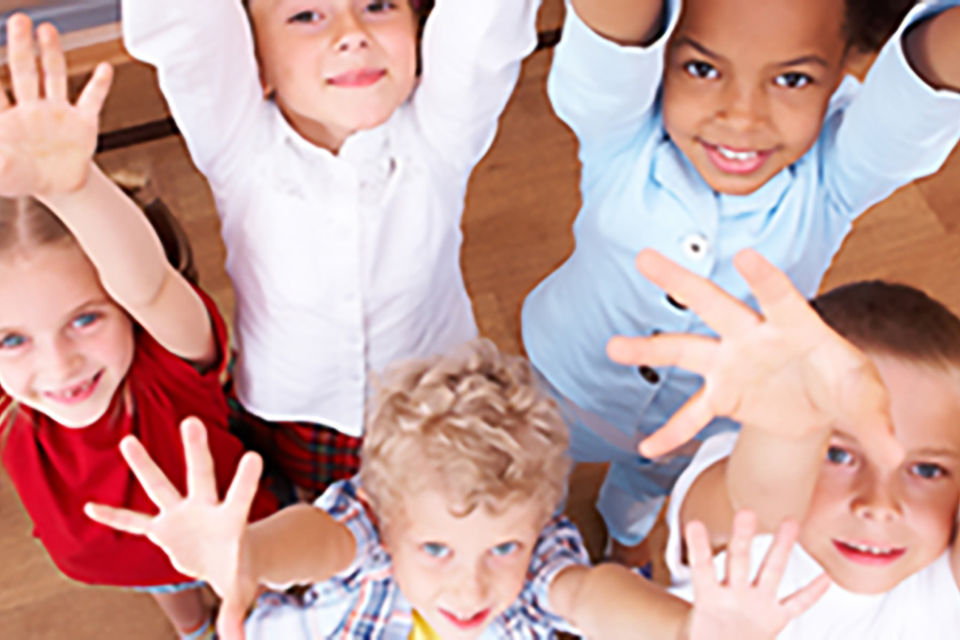 Kinder stehen mit den Händen nach oben in einem Kreis