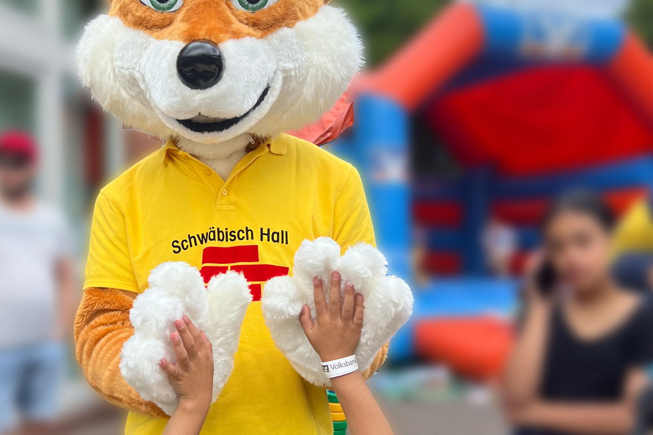 Bausparfuchs macht "High Five" mit einem Kind.