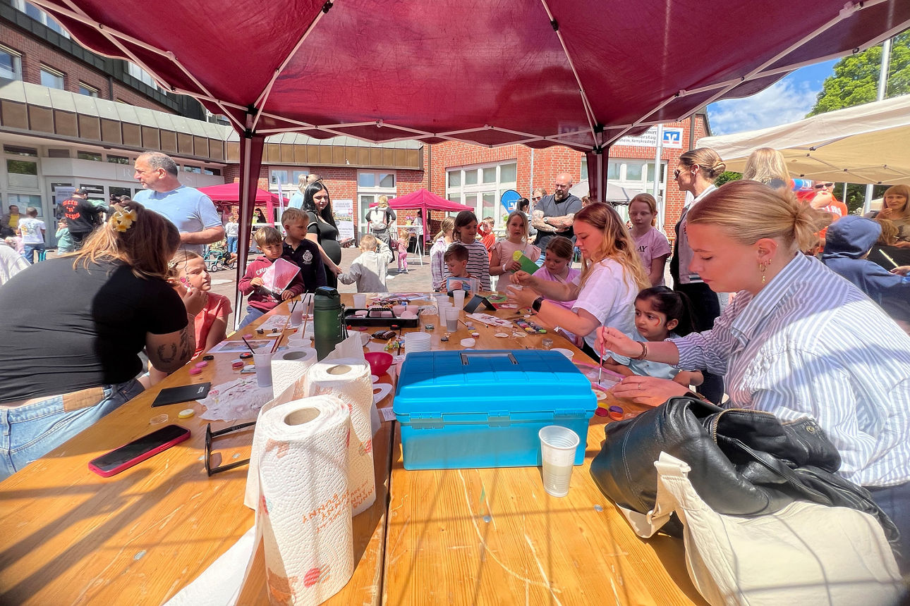 Kinderschminktisch mit Erwachsenen, die die Kindern im Gesicht bemalen auf dem Kindertag in Schermbeck.