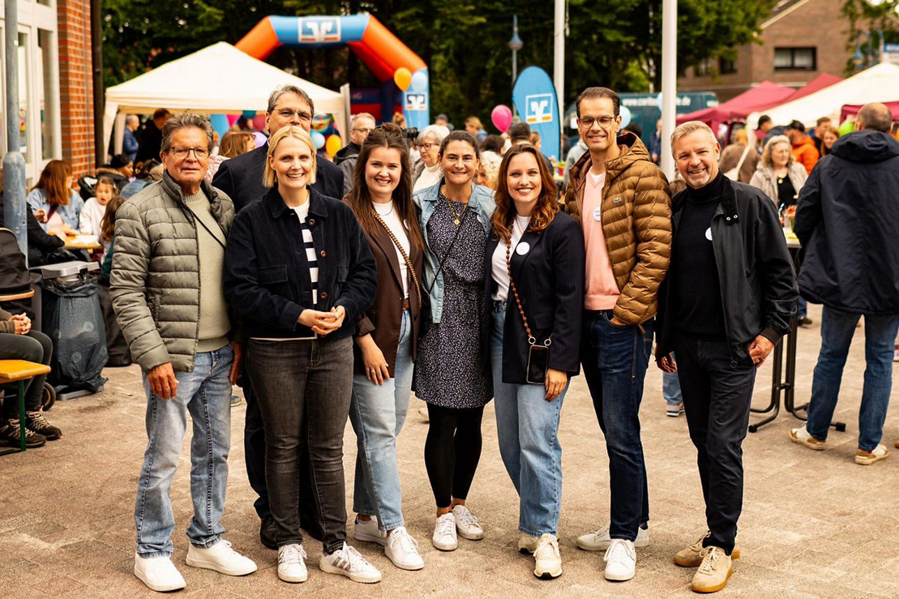 Eine Gruppe mit Frauen und Männern steht zum Gruppenbild aufgestellt. Im Hintergrund ist die Hüpfburg der Volksbank Schermbeck  zu sehen.