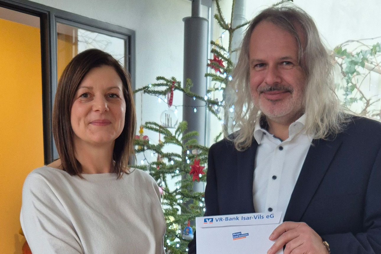 Eine Frau und ein Mann lachen in die Kamera. Sie schütteln sich die Hände.