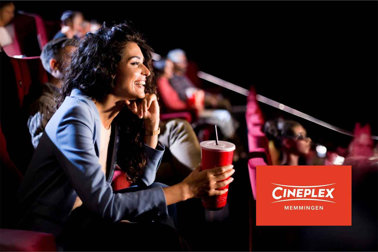 Frau sitzt gespannt im Kino und lacht