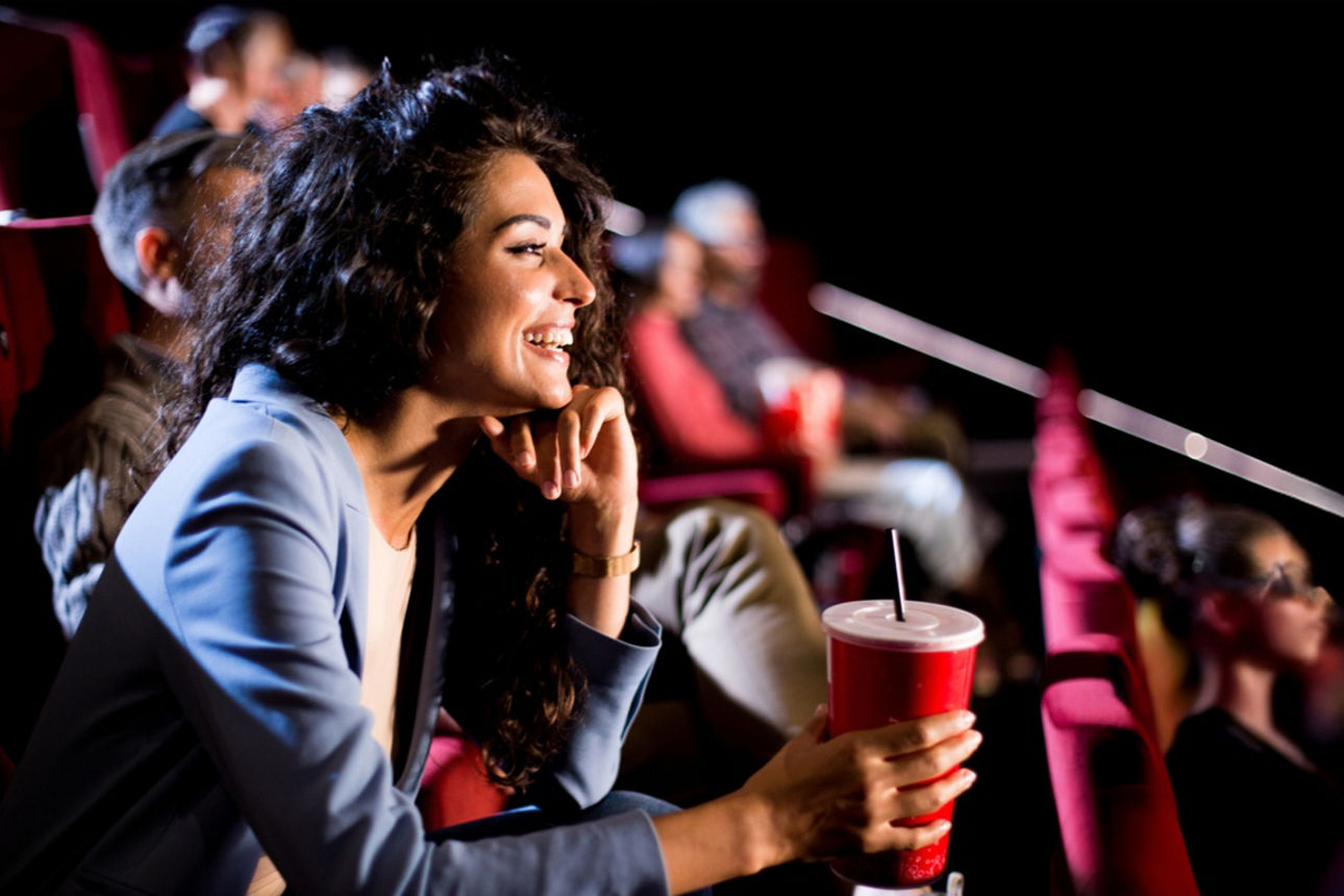 Frau sitzt gespannt im Kino und lacht