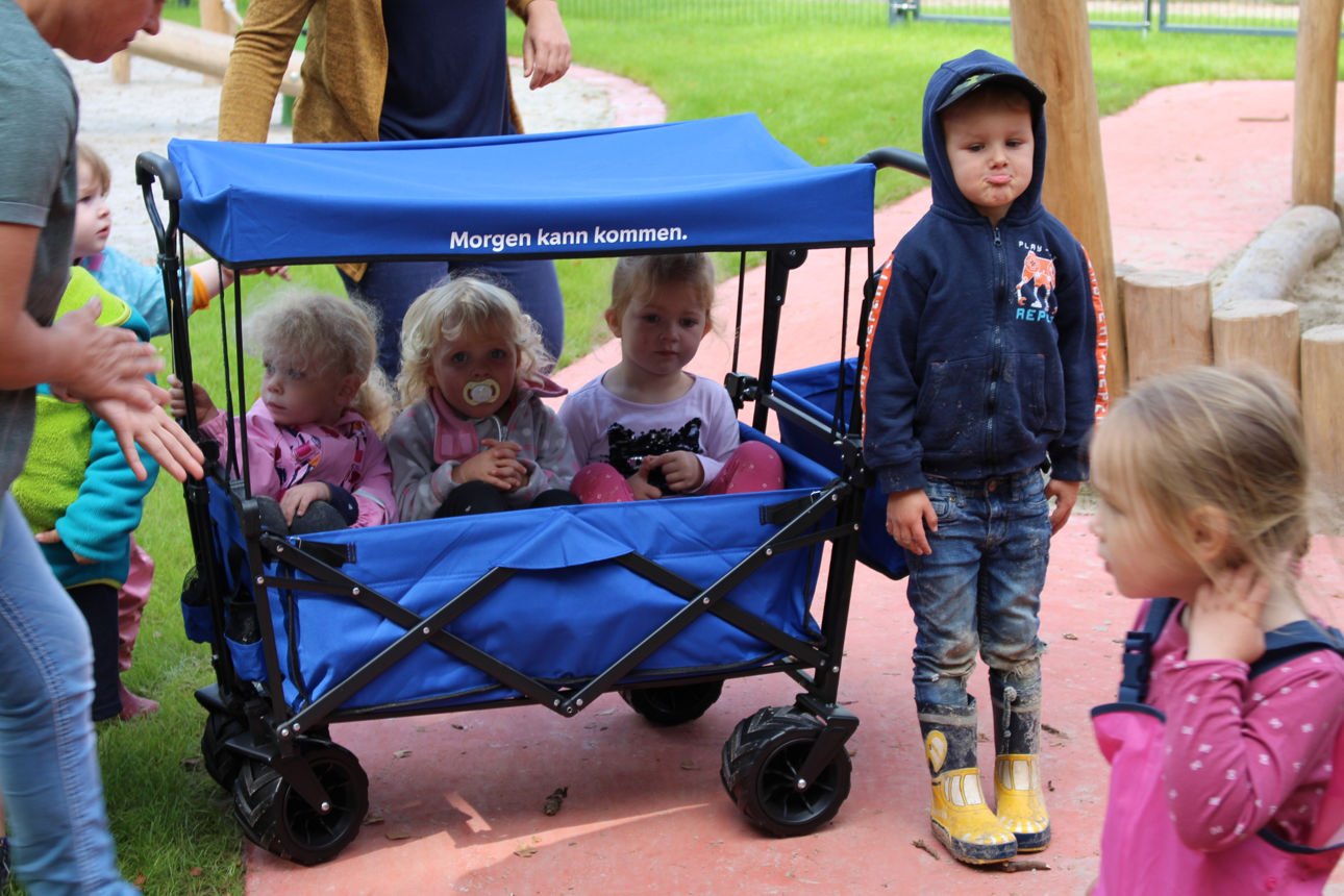 Kinder draußen am Bollerwagen