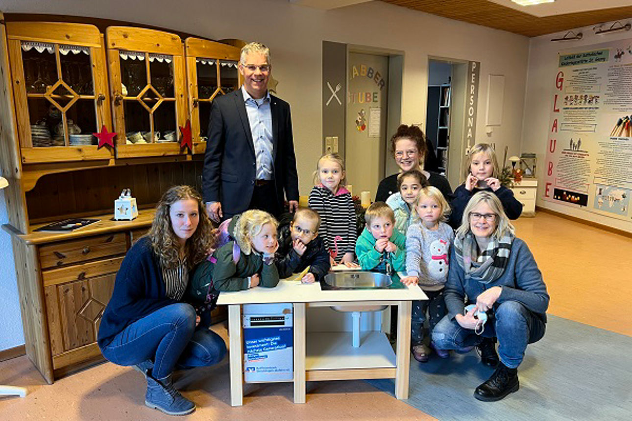 Gruppe von Kindern mit Erzieherin und Vorstand an der Matschküche