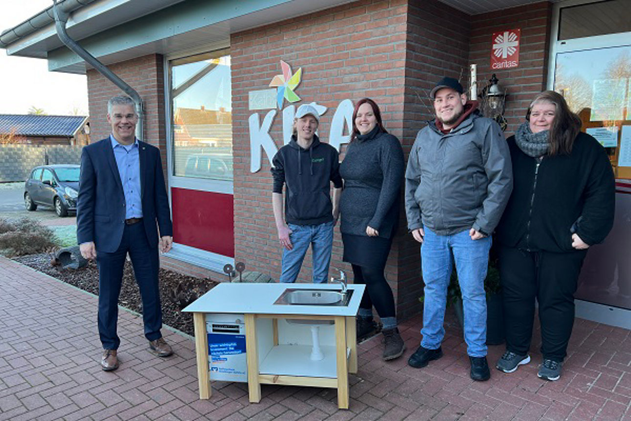 Gruppe von Kindern mit Erzieherin und Vorstand an der Matschküche