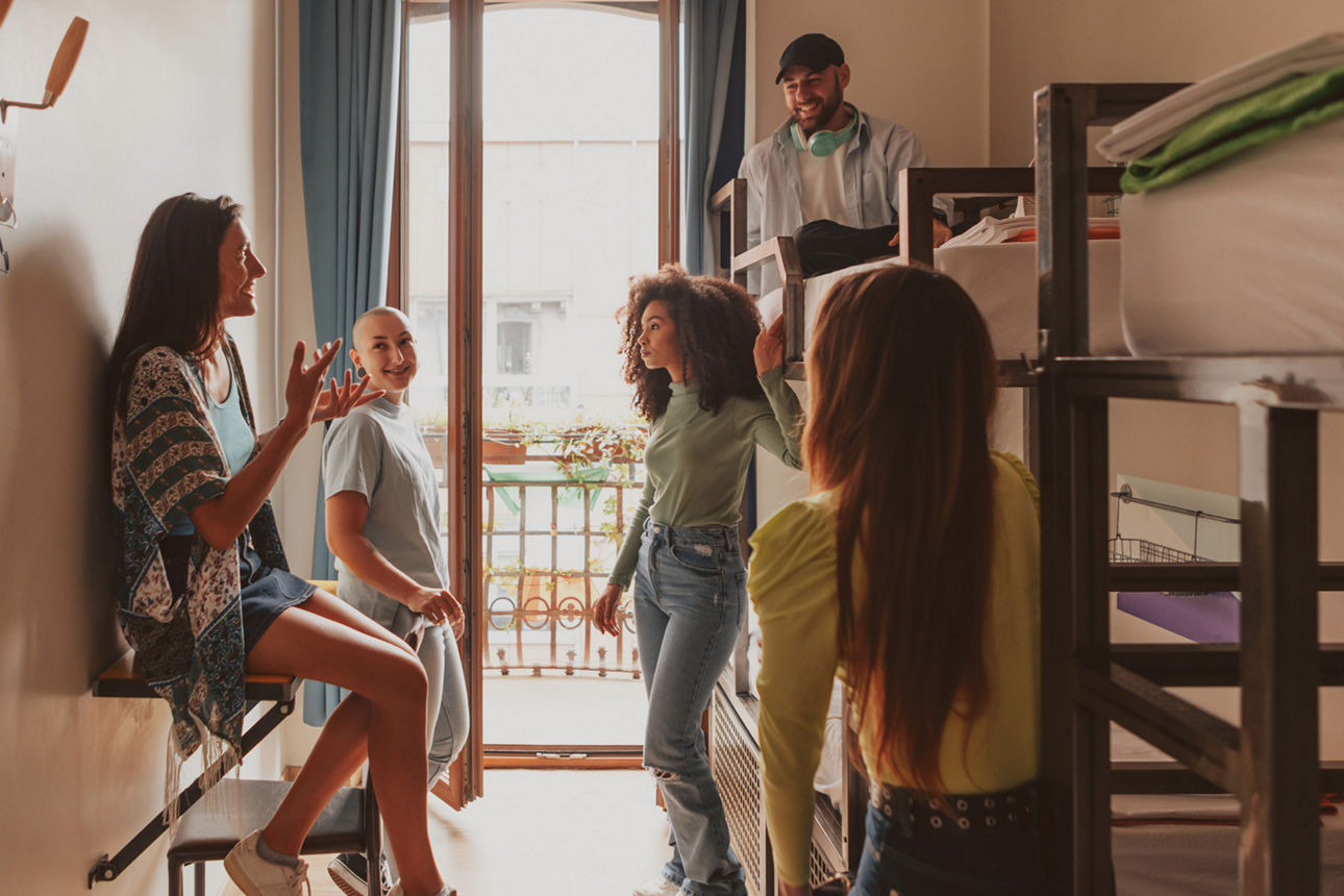 5 junge Leute stehen im Hostel vor den Etagenbetten