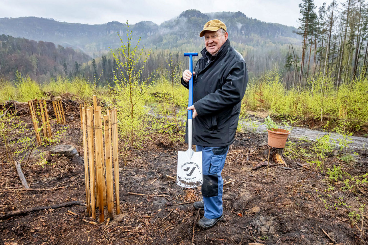 Mann mit Spaten lächelt in Kamera
