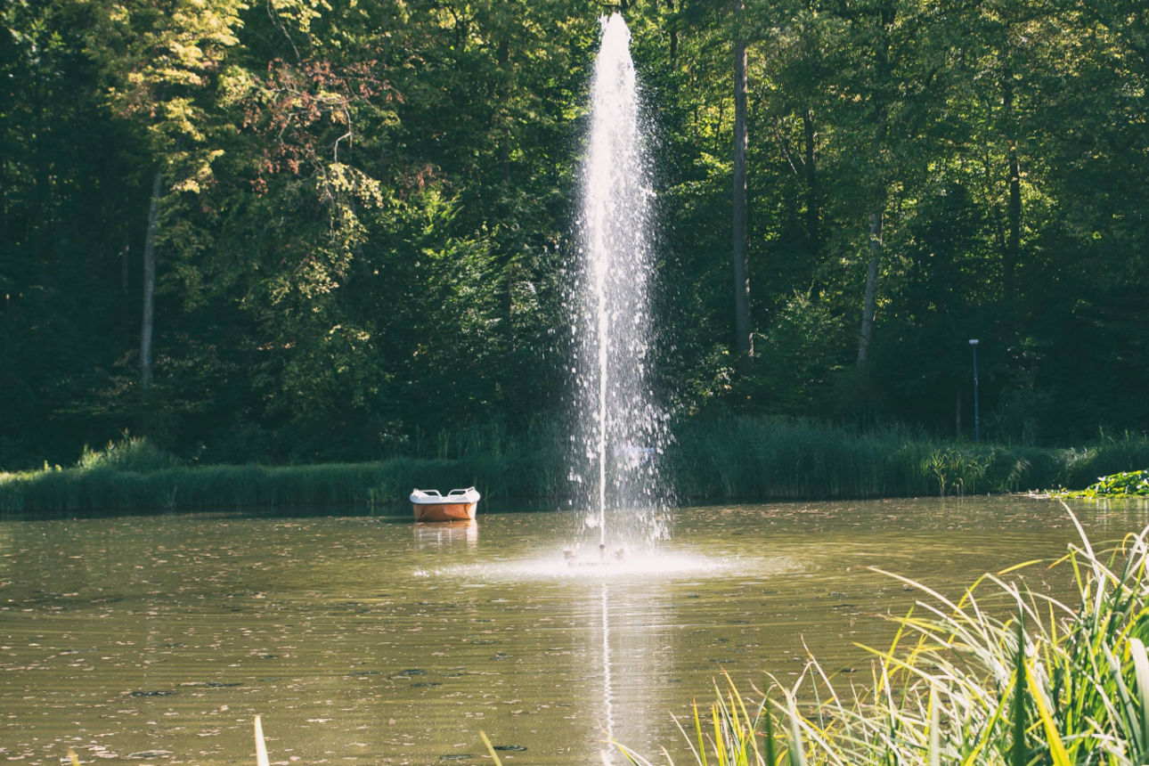 Kleines Boot auf einem ruhigen See mit Wasserfontäne